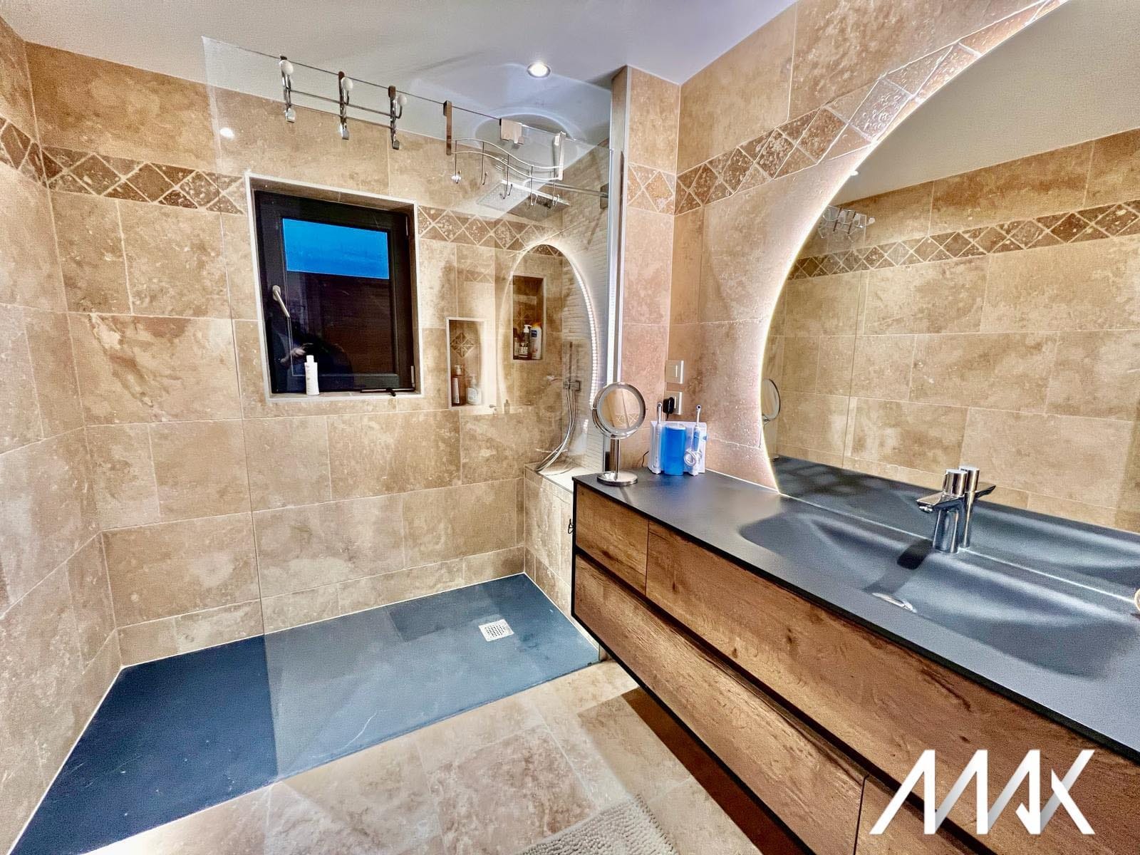 Salle de bain en travertin avec douche à l’italienne réalisée par SASU Max